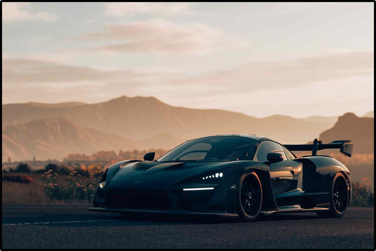 Luxurious black sports car cruising on a winding asphalt road.